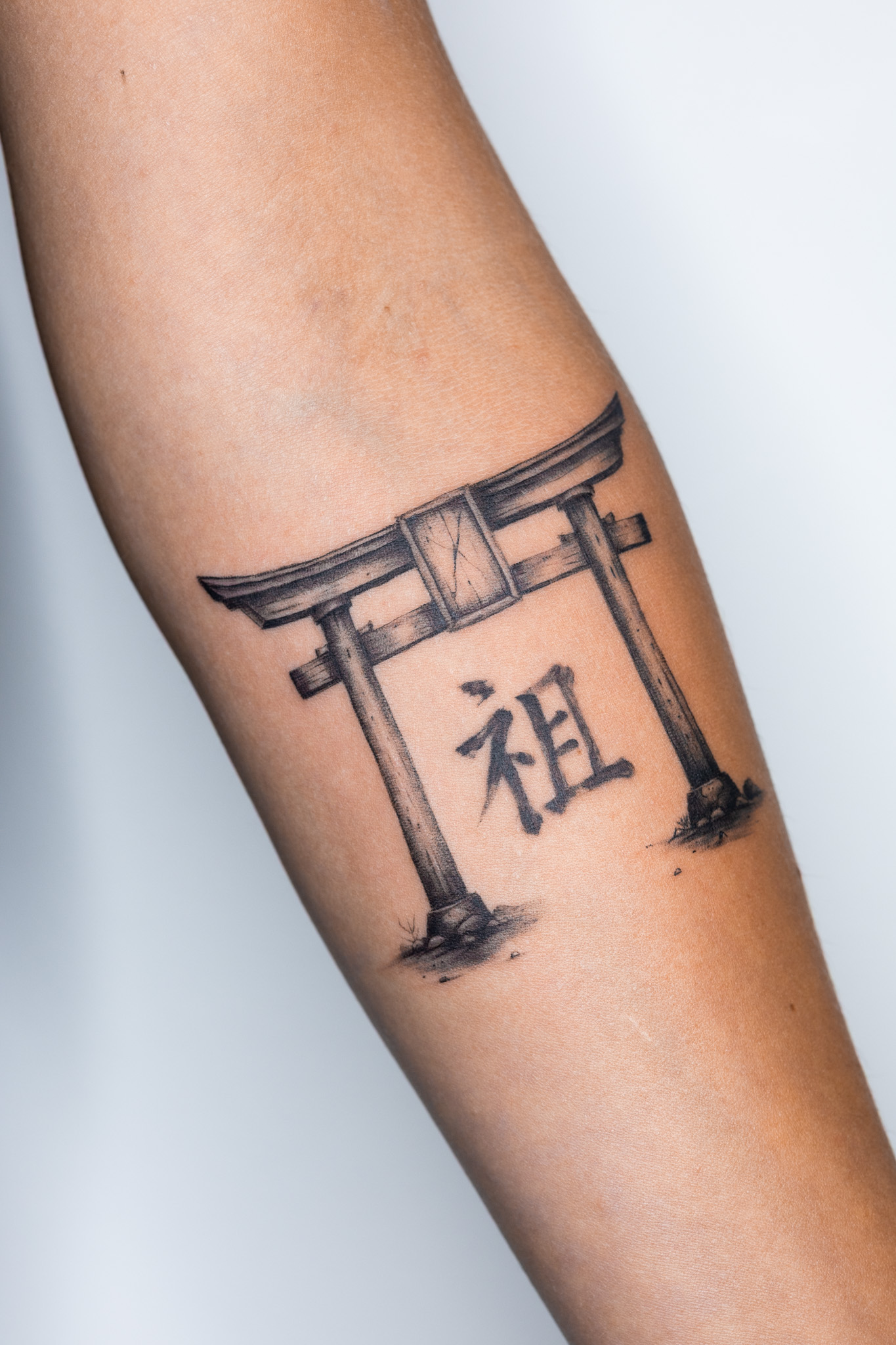 Tatouage torii japonais noir et gris avec symbole japonais sur l’avant-bras